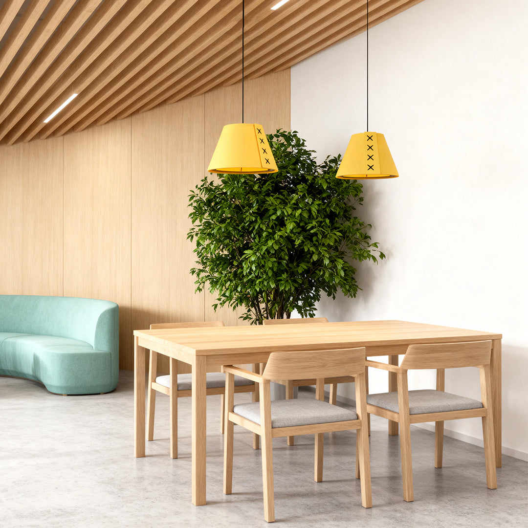 Two yellow hanging pendant lights over a natural wood dining table in a modern commercial space