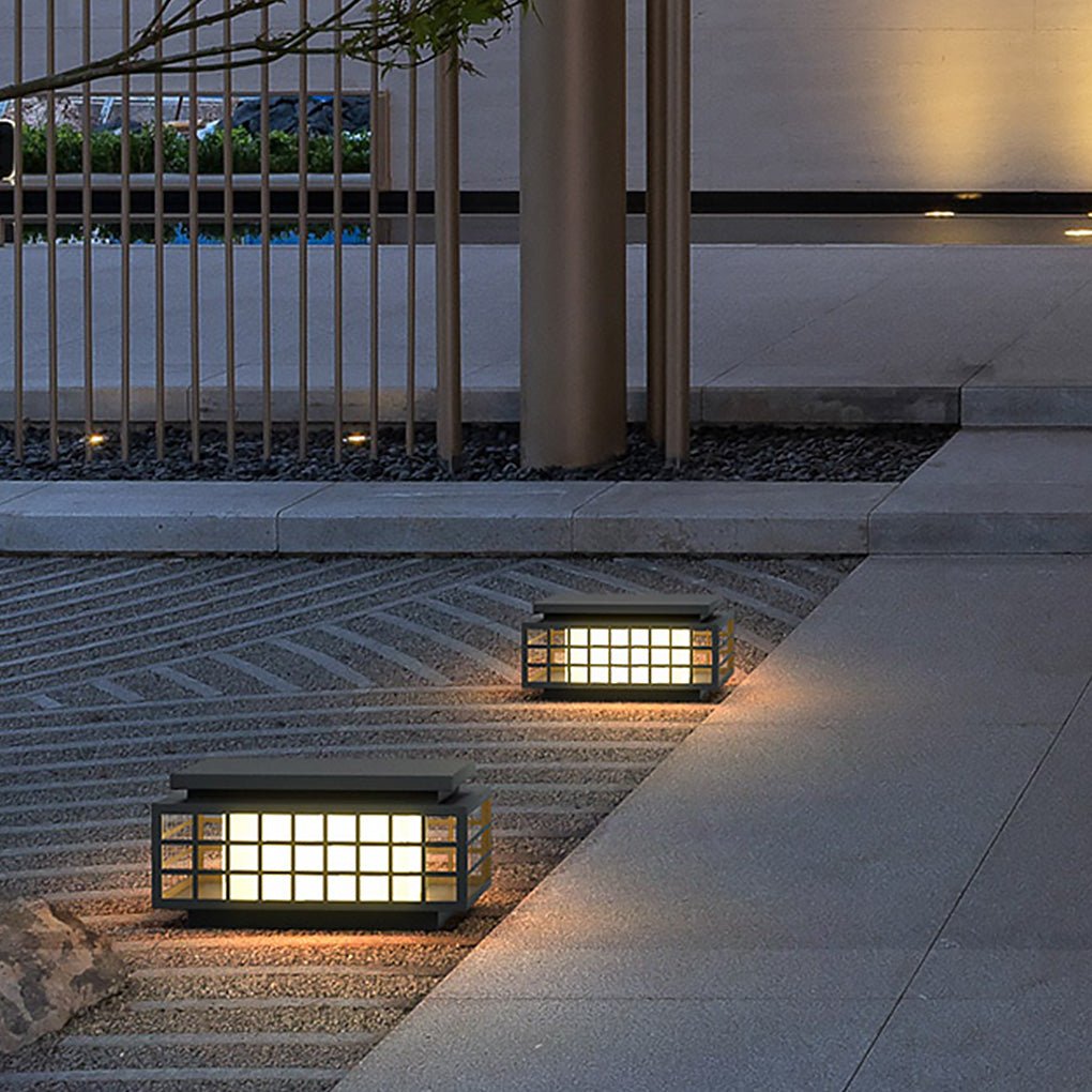 Zen garden light casting light on a stone pathway beside a modern house.